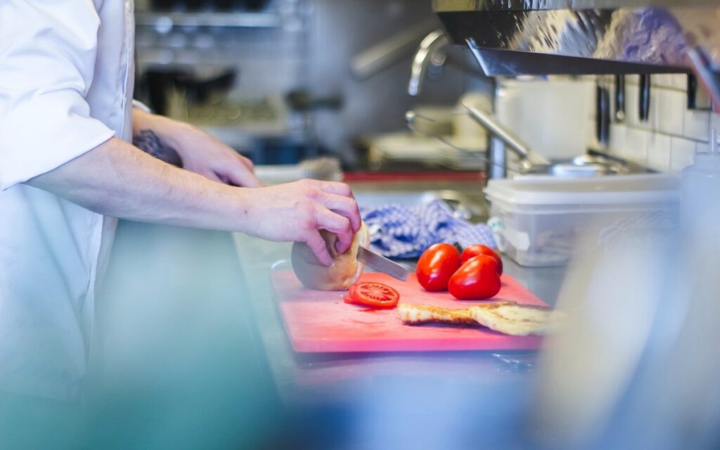 Chef cutting up food on a cutting board with cross contamination.